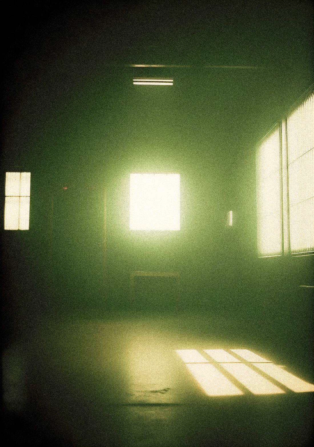 A dim room with two windows at one end, the only bright things in it the windows themselves and two small patches of light on the floor